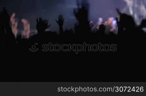 Slow motion of people on rock or pop concert waving hands to the favorite music rhythms, singer performing on the stage