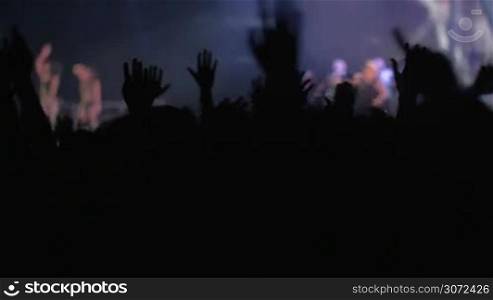 Slow motion of people on rock or pop concert waving hands to the favorite music rhythms, singer performing on the stage
