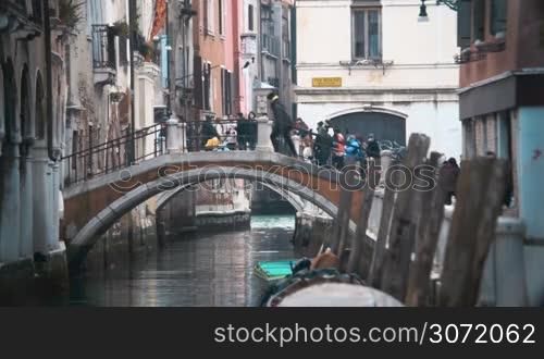 Slow motion of people walking on the bridge across the canal in Venice. Cityscape with old architecture