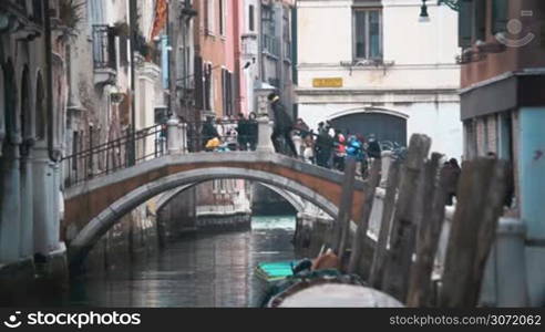 Slow motion of people walking on the bridge across the canal in Venice. Cityscape with old architecture