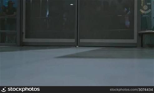 Slow motion of two men with rolling bags walking through the automatic doors of airport terminal