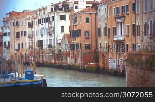 Slow motion of Venice canal with still water, old vintage style houses and moored boat. Classic Venetian cityscape