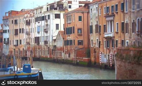 Slow motion of Venice canal with still water, old vintage style houses and moored boat. Classic Venetian cityscape