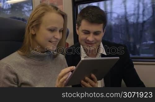 Slow motion of young man and woman having joyful journey in the train. The laughing while watching something funny or humorous on tablet computer