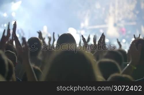 Slow motion shot of a concert audience applauding to the artist during the show.