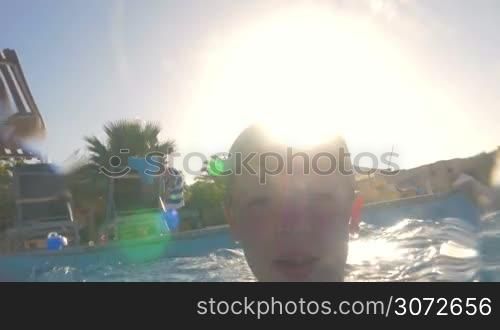 Slow motion shot of a little boy swimming under water on his father&acute;s back.