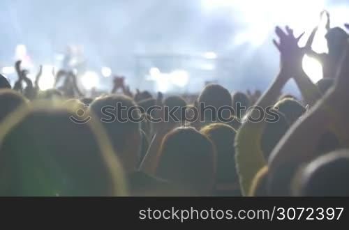 Slow motion shot of a musical conert public applauding to the performer.