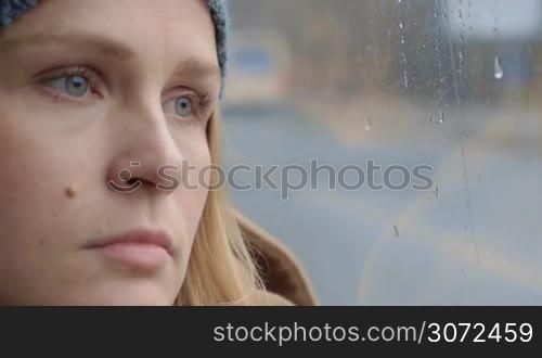 Slow motion shot of a tired woman by the window, there is rainy weather outside.