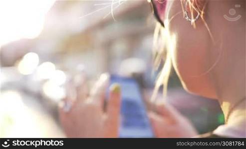 Slow motion shot of a woman browsing web on smart phone in the street. She surfing internet and scrolling the screen down