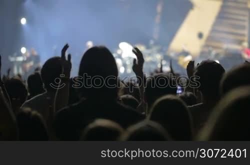 Slow motion shot of an audience of musical concert welcoming the artists&acute; appearance on the stage.
