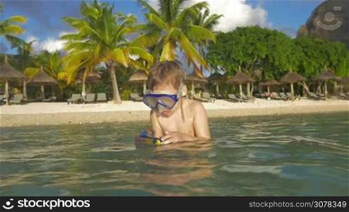 Slow motion shot of child in snorkel diving and making underwater shots with waterproof camera. Fun in water on vacation