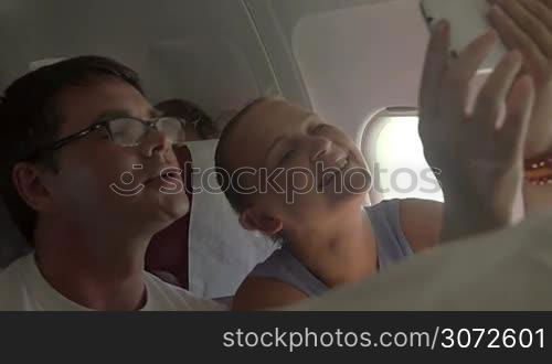 Slow motion shot of couple on the plane taking selfie on smartphone. They are satisfied with the result.