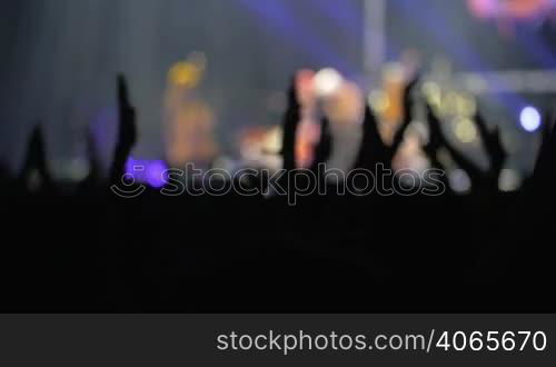 Slow motion shot of hands raised over the head to applaud to the artist on the stage.