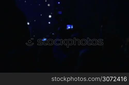 Slow motion shot of people on the musical concert. People are dancing, taking photos, girls are sitting on shoulders of their friends.