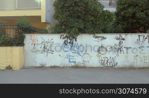 Slow motion steadicam shot of a man and woman doing physical exercises in the city. She having jumping rope workout while man doing push-ups against the wall with graffiti