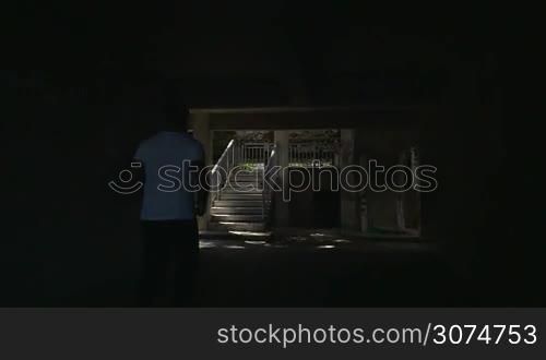 Slow motion steadicam shot of a young man running upstairs in the hotel. He passing several outdoor stairways