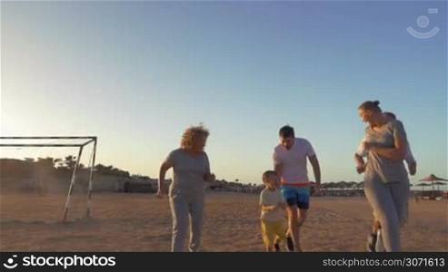 Slow motion steadicam shot of big happy family finishing evening run on the beach and giving high-fives to each other