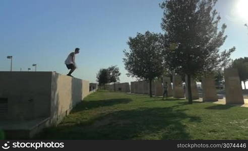 Slow motion steadicam shot of doing dangerous parkour trick. Young man jumping from the wall and doing somersault in the air. Thirst for adrenalin