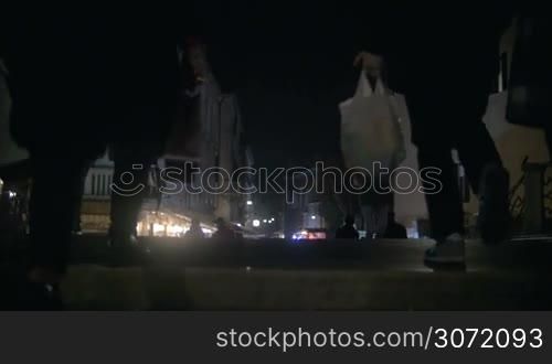 Slow motion steadicam shot of people walking in the Venetian street with shops and outdoor cafe in the evening. No visible faces