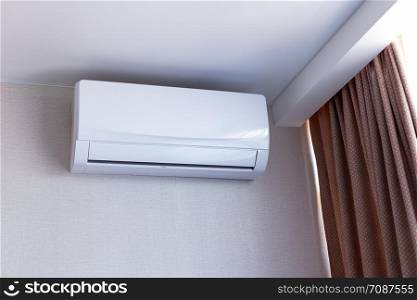 Small air conditioning on the wall inside room in apartment, switched off. Interior in calm beige tones.
