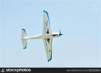 Small airplane flying against blue sky at airshow