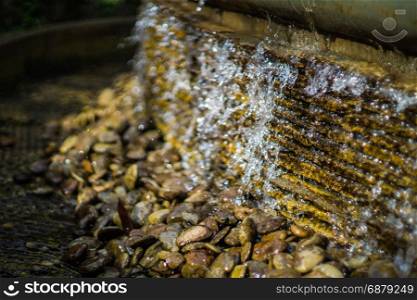 Small artificial waterfall with splash and bokeh in the garden