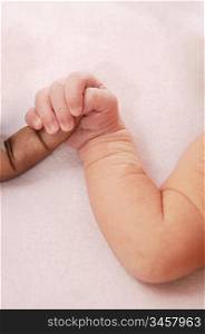 Small baby caucasian hand holding african finger