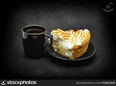 Small black cup of coffee and piece and a piece of meringue cake.
