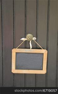 Small blackboard on a door, hanging on small rope