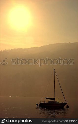 Small boat anchored in quite lake water at sunset