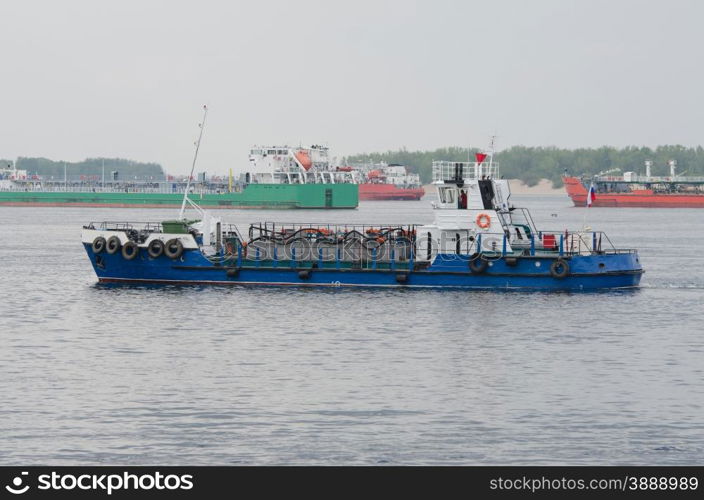 small boat on background of standing in the roads tankers. A small boat floats past standing in the roads tankers