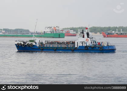 small boat on background of standing in the roads tankers. A small boat floats past standing in the roads tankers