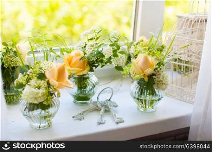 Small bouquets of beautiful roses and bunch of old keys on the windowsill.. White decoration of the room