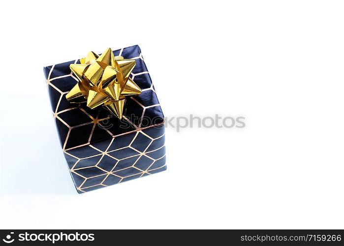 small box in black wrapping paper with a gold geometric pattern and a gold bow. Isolate on a white background.