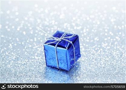 Small box with decorative holiday gift on silver bokeh background