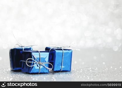 Small boxes with decorative holiday gifts on silver bokeh background