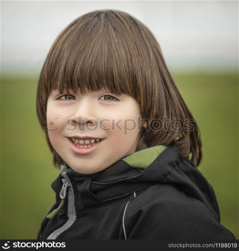 Small boy portrait on green background at autumn