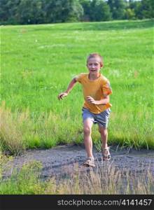 Small boy running on green meadow, summertime