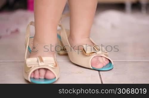 Small boy wearing his mothers high heeled open-toed shoes and then walking in them, close up of his feet in the shoes