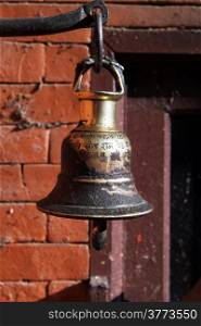 Small bronze bell hang near the brick wall in the temple
