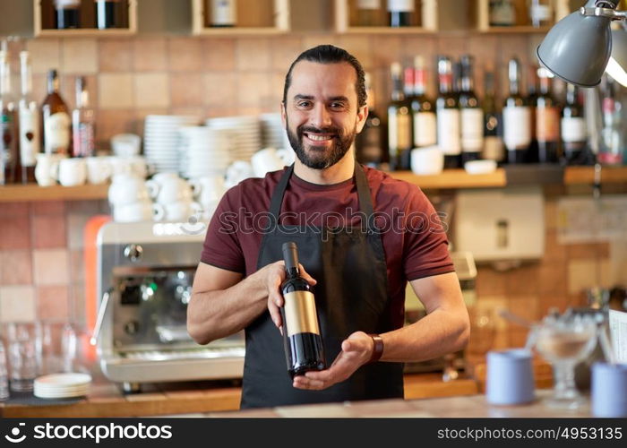 small business, alcohol drinks, people and service concept - happy man or waiter with bottle of red wine at bar. happy man or waiter with bottle of red wine at bar