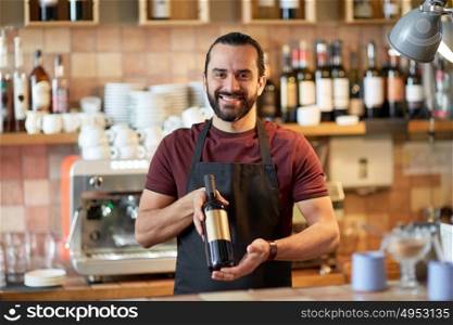 small business, alcohol drinks, people and service concept - happy man or waiter with bottle of red wine at bar. happy man or waiter with bottle of red wine at bar