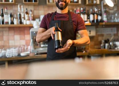 small business, alcohol, people and service concept - happy man or bartender with bottle of wine at restaurant bar . happy man or bartender with bottle of wine at bar