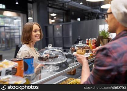 small business, food, people and service concept - happy man or barman with cake serving female customer at vegan cafe. man or barman with cake serving customer at cafe