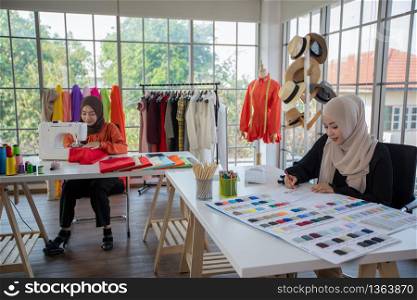 Small business of Muslim woman fashion designer Working and using smart phone and tablet With Dresses at clothing store