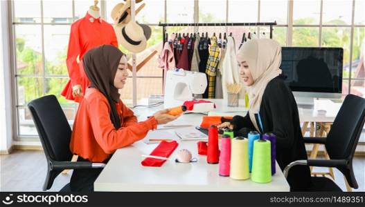 Small business of Muslim woman fashion designer Working and using smart phone and tablet With Dresses at clothing store