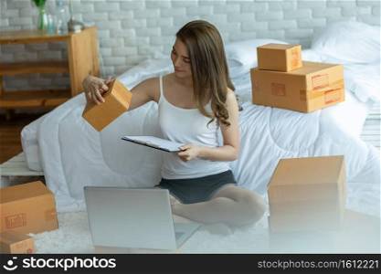 Small Business of young asian woman woking at home,Businesswoman working with laptop for Online shopping at home,Cheerful and Happy with box for order packaging in home,Own Business Start up concept