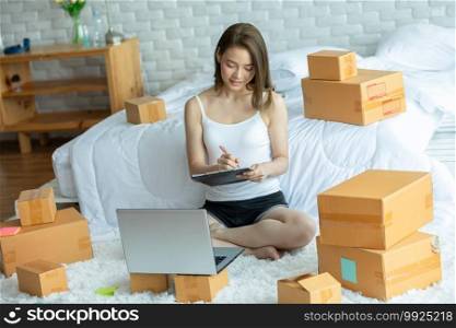 Small Business of young asian woman woking at home,Businesswoman working with laptop for Online shopping at home,Cheerful and Happy with box for order packaging in home,Own Business Start up concept