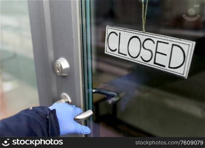 small business, pandemic and service concept - hand in medical glove holding to door knob of closed shop. hand in medical glove holding to closed door