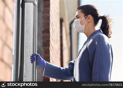 small business, pandemic and service concept - woman in face protective medical mask and glove holding to office door handle. woman in mask and glove holding to door handle